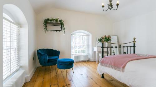 Un dormitorio con una cama y una silla azul. en Ty Capel Mawr, en Menai Bridge