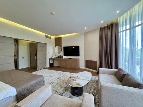 een woonkamer met een bed, een bank en een tv bij Donatello Boutique Hotel in Alma-Ata