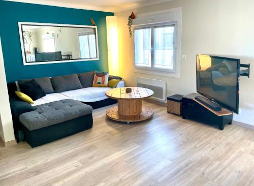 a living room with a couch and a table and a tv at La Maison Nikaïa in Narbonne