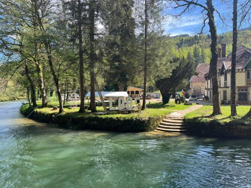 une rivière avec des arbres et une maison en arrière-plan dans l'établissement Best price#room ST LOUP 1, à Lods