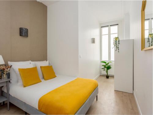 - une chambre blanche avec un lit et des oreillers jaunes dans l'établissement Merveil - Family Suite - Champs Elysees - Wagram, à Paris