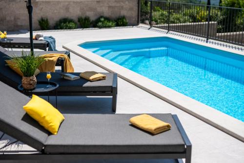 a swimming pool with two chaise lounges next to a swimming pool at Villa Casa de Flores in Dubravka