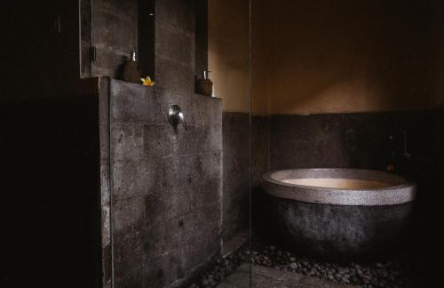 a dark bathroom with a tub and a glass wall at Bucu View Resort in Ubud
