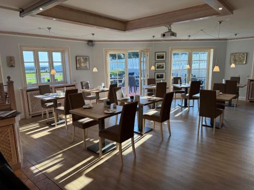 a dining room with tables and chairs and windows at Haus Amanda in Norddorf