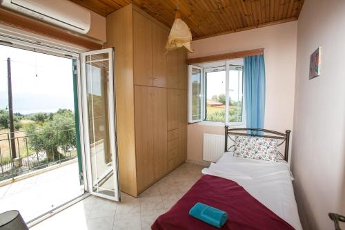 ein Schlafzimmer mit einem Bett und einem großen Fenster in der Unterkunft Evaggelatos Cottage in Lixouri