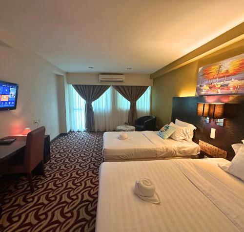 a hotel room with two beds and a desk and a television at Greenage MingSuite 明绿时代套房 Kota Kinabalu 亚庇市中心 in Kota Kinabalu