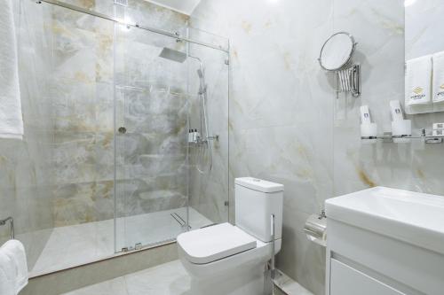 a bathroom with a shower and a toilet and a sink at Clouds Hotel in Tashkent