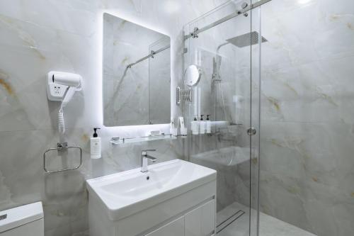a white bathroom with a sink and a shower at Clouds Hotel in Tashkent