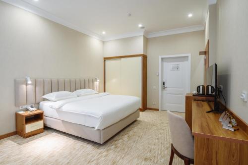 a bedroom with a bed and a desk and a television at Clouds Hotel in Tashkent