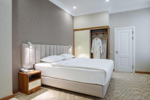a bedroom with a large white bed and a closet at Clouds Hotel in Tashkent