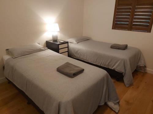 two beds in a room with a lamp on a table at 28-32 Boisdale 2 Br in Mont Albert