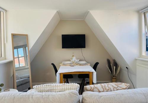 a living room with two couches and a tv at tiny beach house noordwijk in Noordwijk aan Zee