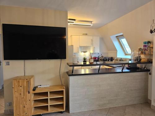 une cuisine avec une grande télévision murale à écran plat dans l'établissement Spot idéal à 800m de la plage, à Blonville-sur-Mer