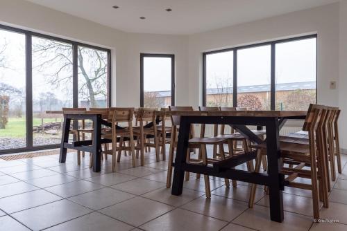 a dining room with a table and chairs and windows at 14 beds, 20p, 2 bath-, 1 livingroom in Houthalen-Helchteren