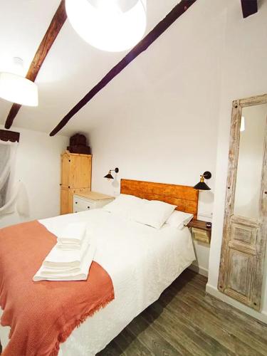 a bedroom with a large white bed and a mirror at La Calderera in Talarrubias