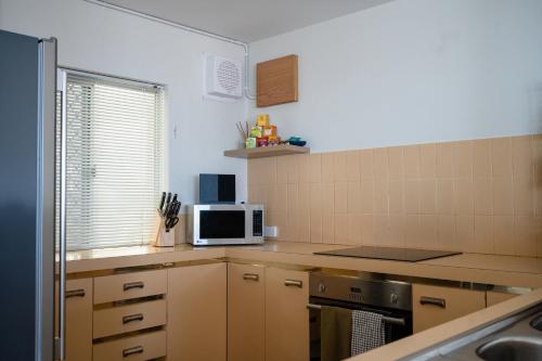 a small kitchen with a microwave and a stove at Cottesloe Beach View Apartments No.8 in Perth