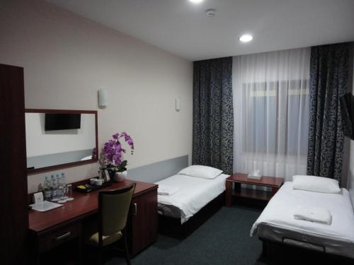 a hotel room with two beds and a desk and a mirror at Hotel Polonia in Biała Podlaska