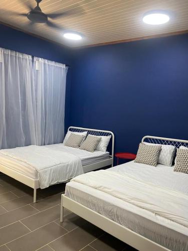two beds in a room with a blue wall at Woodstock Camp Chalet in Bentong