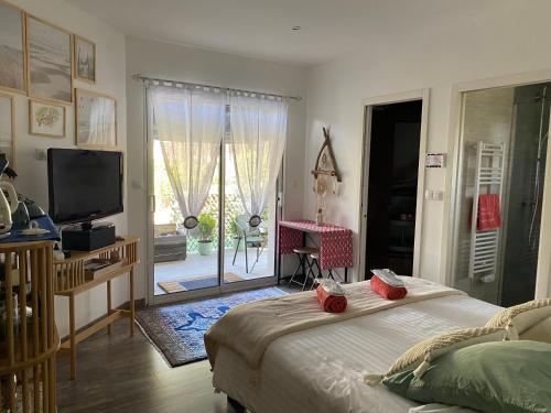 a bedroom with a bed and a television and a balcony at Chambre cosy Andernos Les Bains in Andernos-les-Bains
