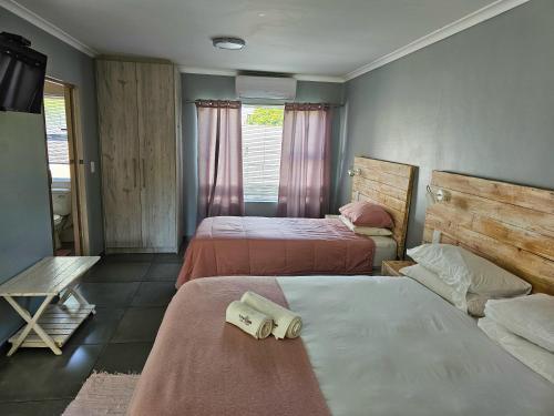 a bedroom with two beds with towels on them at Northern Vine Guesthouse B&B Self-catering in Brackenfell
