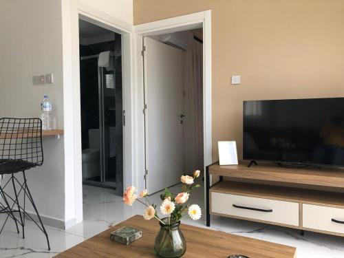a living room with a television and a vase with flowers at Bungalow in a holiday village, Kyrenia in Kérynia