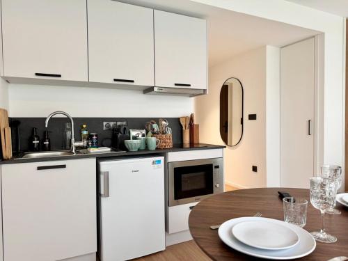 une cuisine avec des armoires blanches et une table en bois dans l'établissement We Live Inn Sharies Reims B303, à Reims