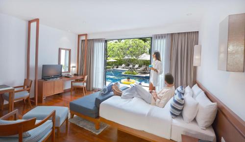 a man and woman sitting on a bed in a hotel room at Woodlands Suites Serviced Residences - SHA Extra Plus in Pattaya North