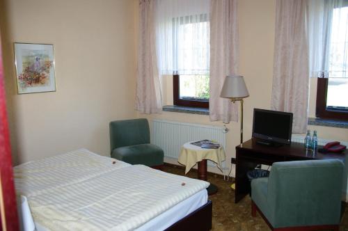 una camera d'albergo con un letto, una scrivania e delle sedie di Landhotel Goldener Löwe mit Pension Am Taurastein a Burgstaedt