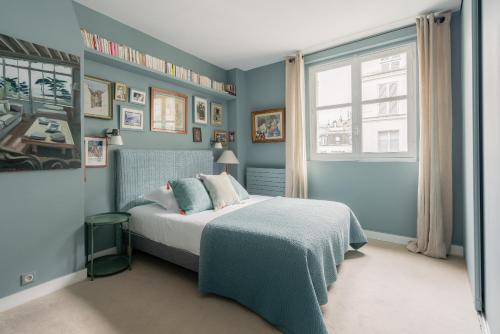 une chambre avec un lit aux murs bleus et une fenêtre dans l'établissement Veeve - Artful Escape, à Paris