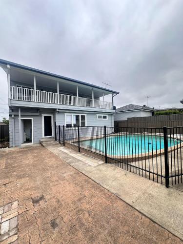a house with a fence next to a swimming pool at Comfortable and Spacious Queen Room - SW2 in Wentworthville