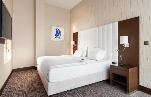 a large white bed in a hotel room at Copernicus Toruń Hotel in Toruń