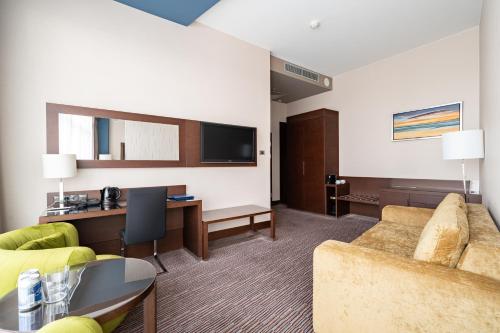a hotel room with a couch and a desk and a tv at Copernicus Toruń Hotel in Toruń