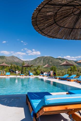 a swimming pool with chairs and an umbrella at Mesopotam Agrotourism Resort in Sarandë