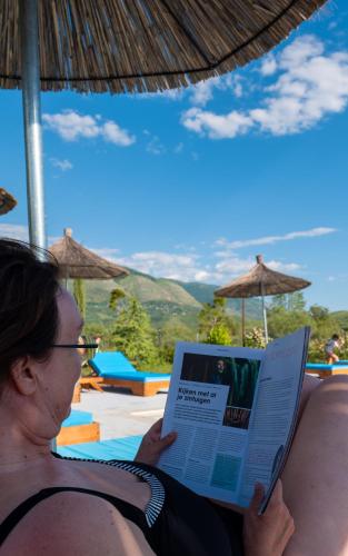 a woman sitting on a couch reading a book at Mesopotam Agrotourism Resort in Sarandë