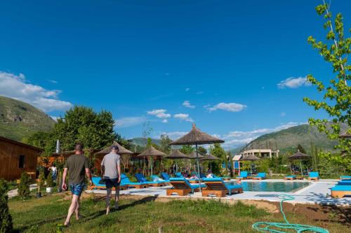two men walking by a pool at a resort at Mesopotam Agrotourism Resort in Sarandë