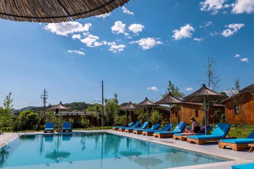 a pool at a resort with blue lounge chairs at Mesopotam Agrotourism Resort in Sarandë