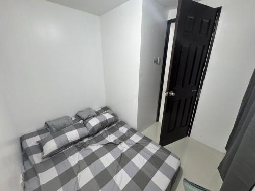 a bedroom with a checkered bed with a black door at D&D Transient House in Sampong