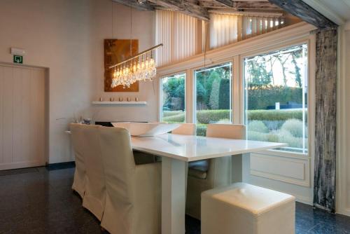 a kitchen with a white table and chairs and a window at Luxe Vacation Villa with swimming pool, 5 bedrooms in Houthalen-Helchteren