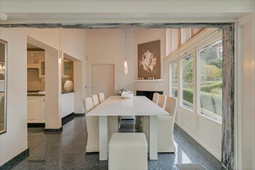 a dining room with a white table and chairs at Luxe Vacation Villa with swimming pool, 5 bedrooms in Houthalen-Helchteren