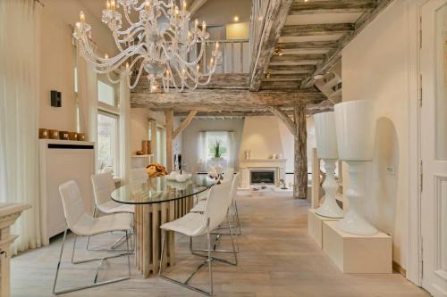 a dining room with a glass table and white chairs at Luxe Vacation Villa with swimming pool, 5 bedrooms in Houthalen-Helchteren