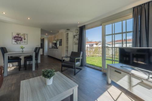 a living room with a television and a table with chairs at Holiday Park Dennenbos in Oostkapelle