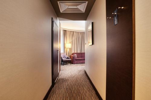 a corridor of a hotel room with a door and a chair at Copernicus Toruń Hotel in Toruń