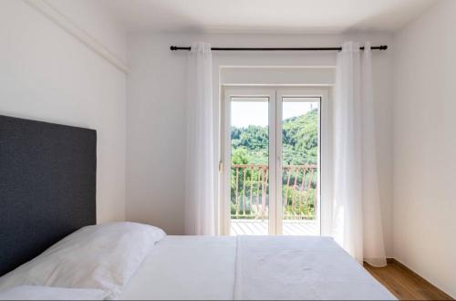 a bedroom with a white bed and a large window at Villa La Domazet in Podstrana