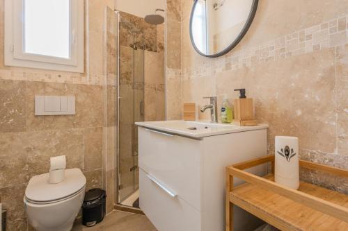 une salle de bain avec toilettes, lavabo et miroir dans l'établissement Nice Magnan, Appartement proches plage et tramway, à Nice