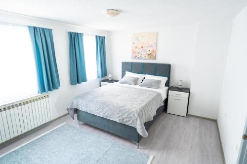 a bedroom with a bed with a blue headboard at Apartman 11 in Tomislavgrad