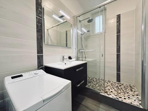 une salle de bain blanche avec un lavabo et une douche dans l'établissement Jadart T3 avec balcon au pied de la cathédrale, à Reims