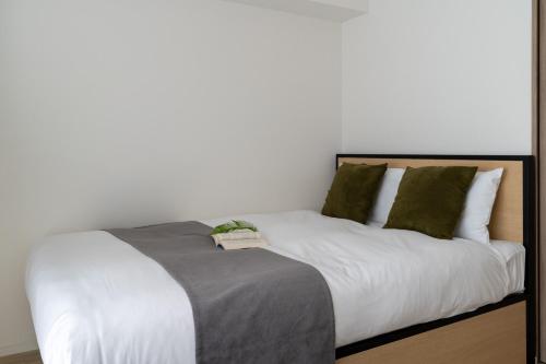 a bed with white sheets and green pillows at GRO-BEL THE KLES Kamata in Tokyo