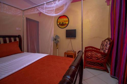 a bedroom with a bed and a chair at Pacific Cottages and Guest House Jinja in Jinja