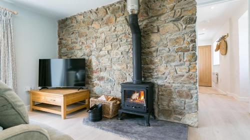 a fireplace in a living room with a stone wall at Bryntirion Wyn in Aberffraw