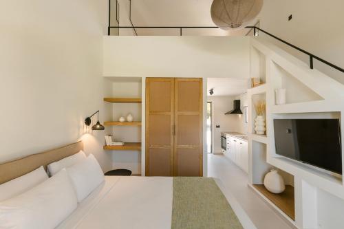 a white room with a bed and a television at Rodi Studios in Karavadhos